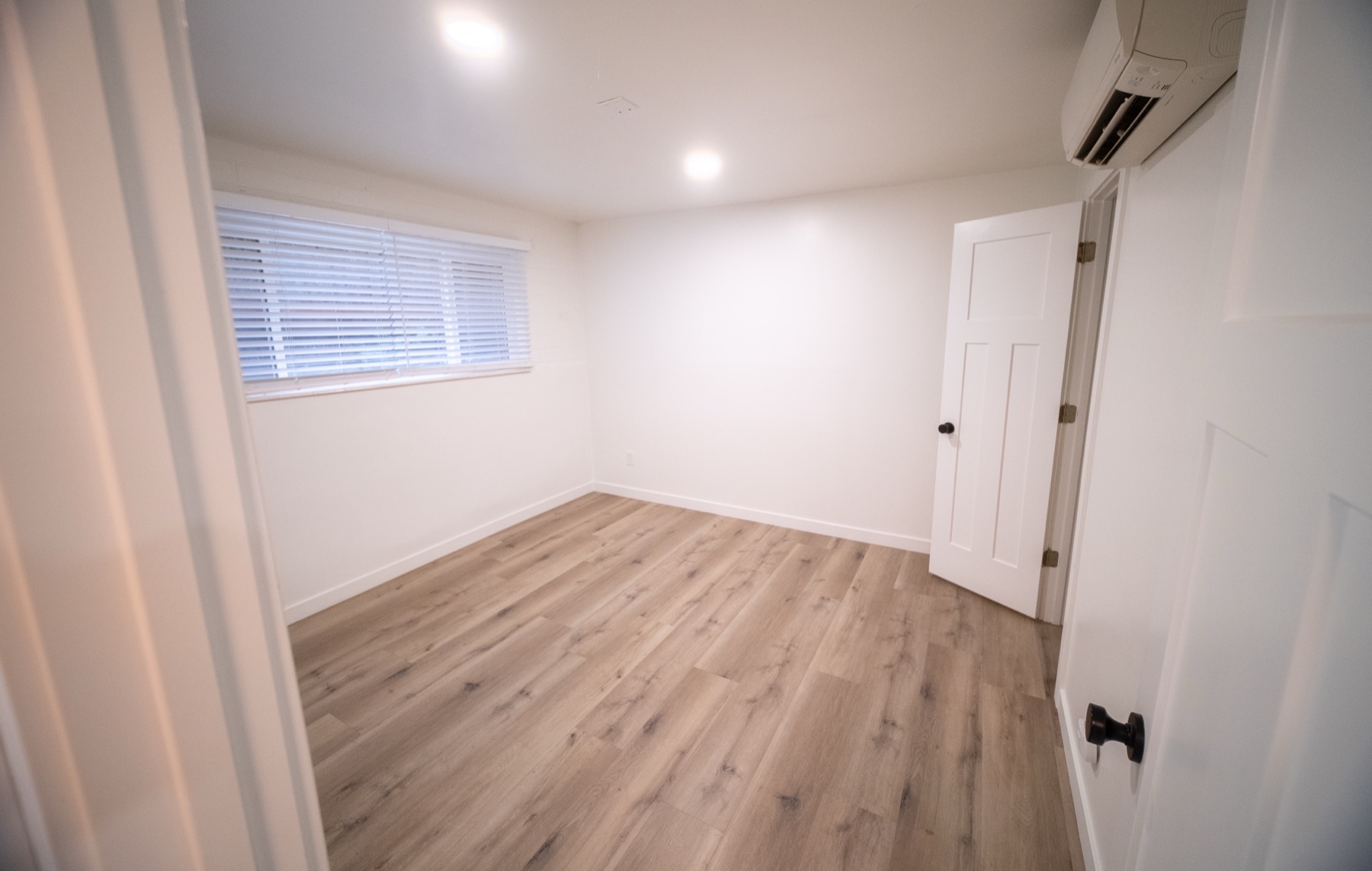 Bedroom with ductless mini-split air conditioning and vinyl plank floors