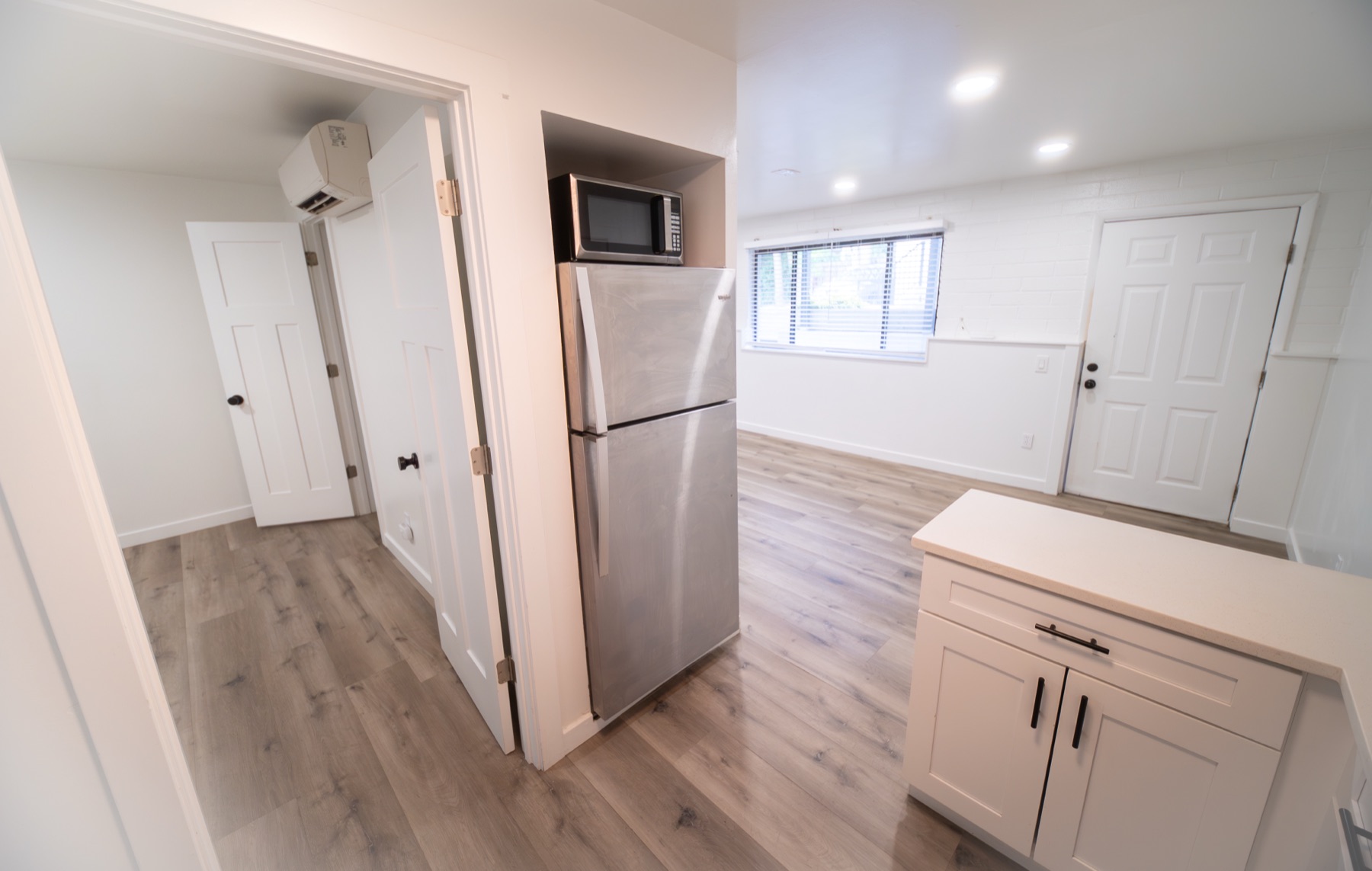 Living and kitchen area with cabinetry, microwave, and window