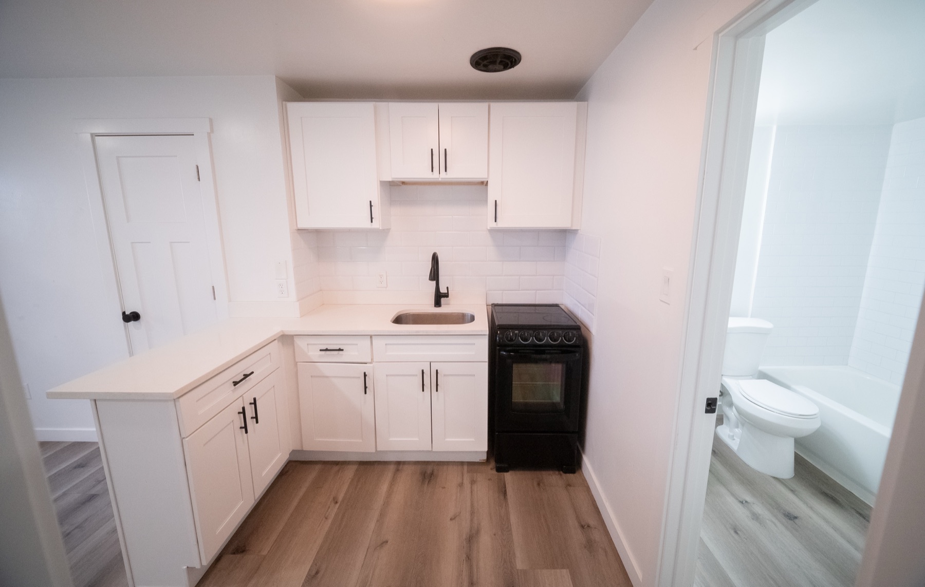 Compact kitchen with white cabinetry, gas range, and sink