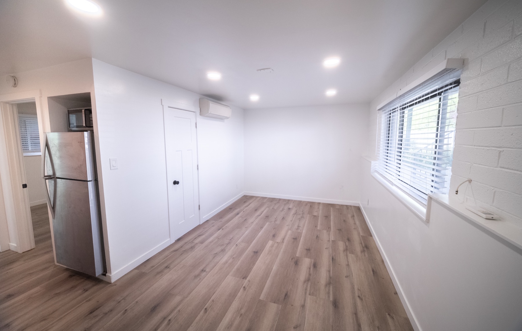Open living area with refrigerator, window, and vinyl plank floors
