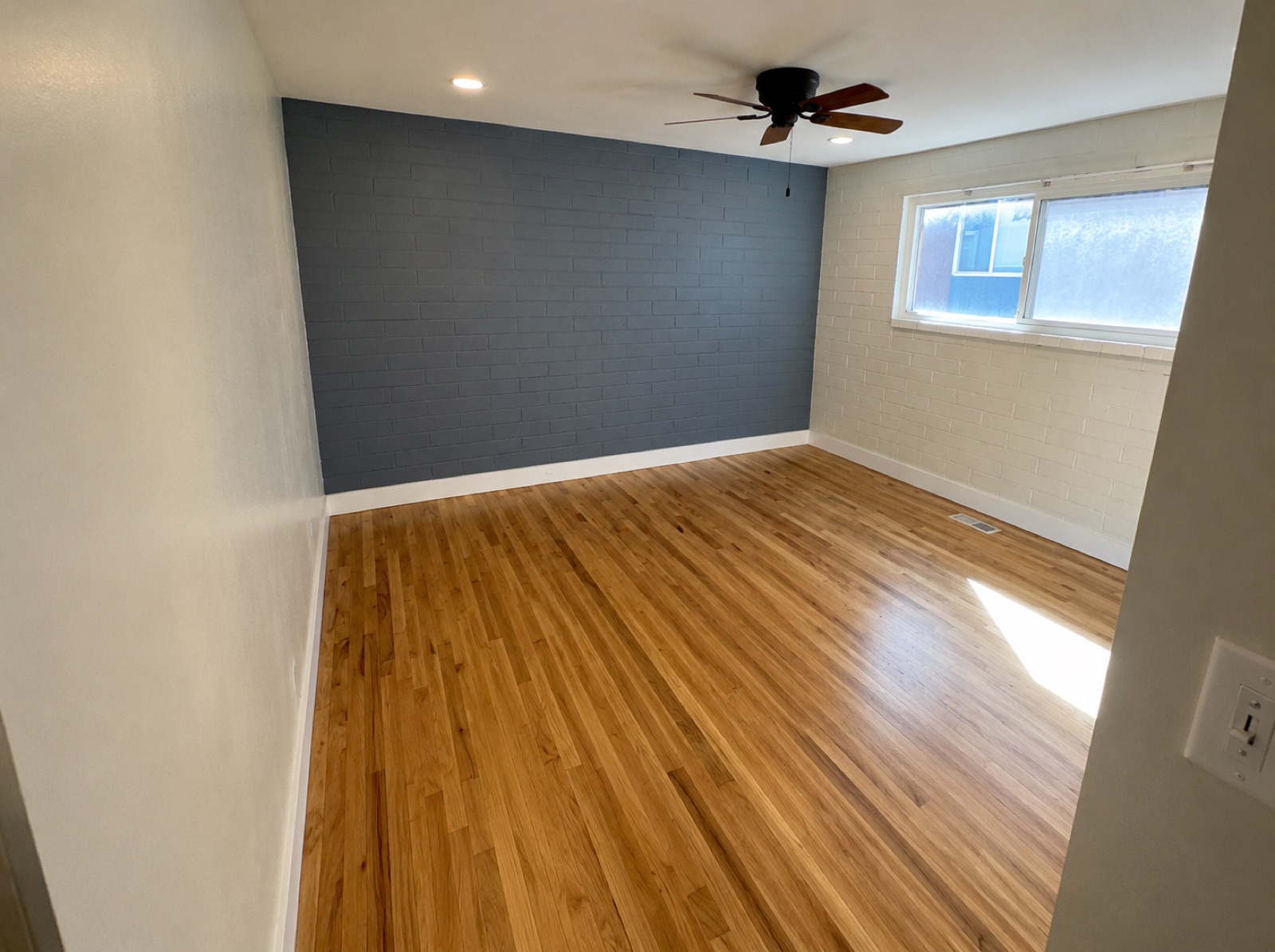 Room with a painted accent brick wall and hardwood floors