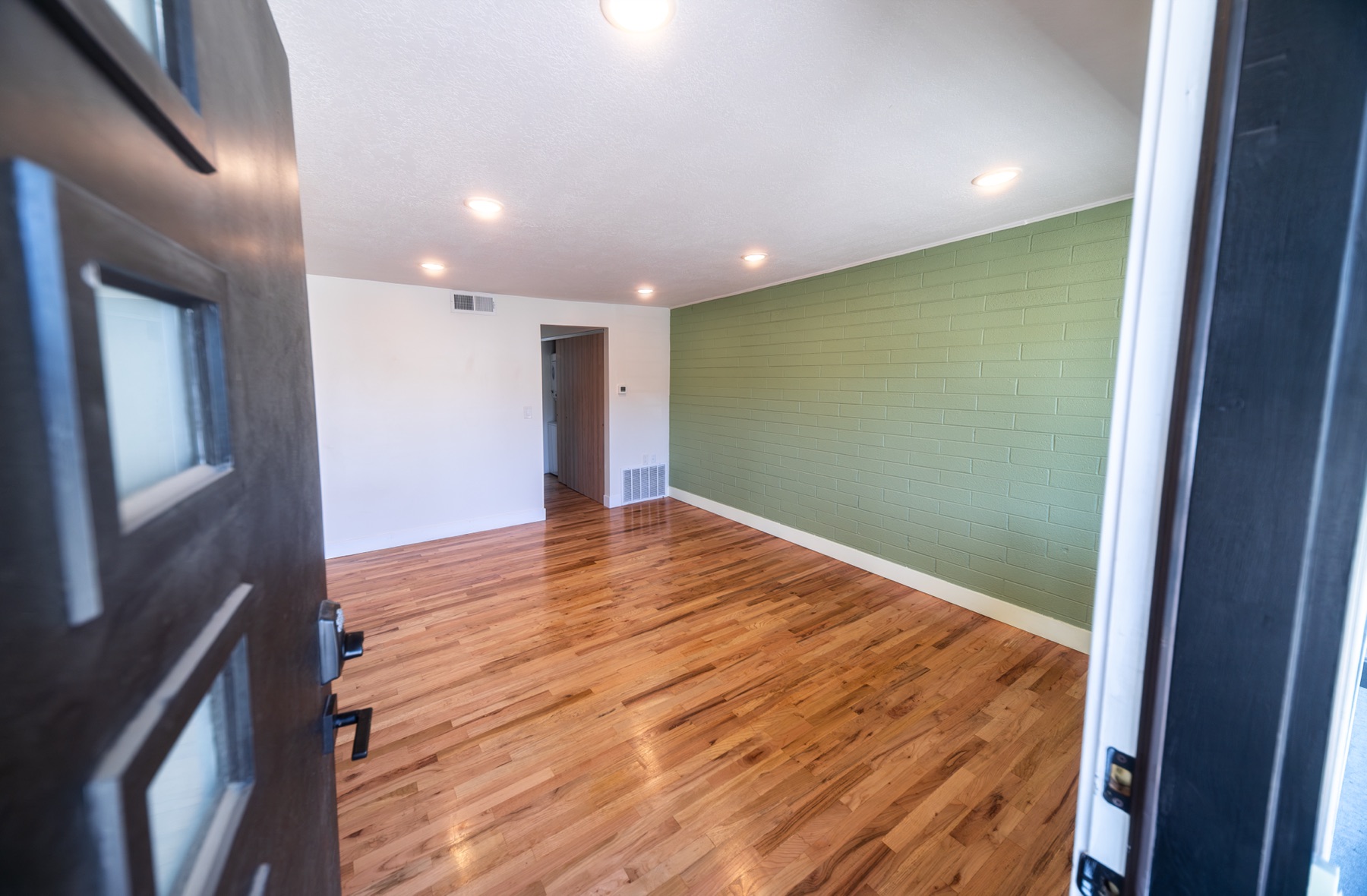 Living room with a green accent wall and hardwood floors