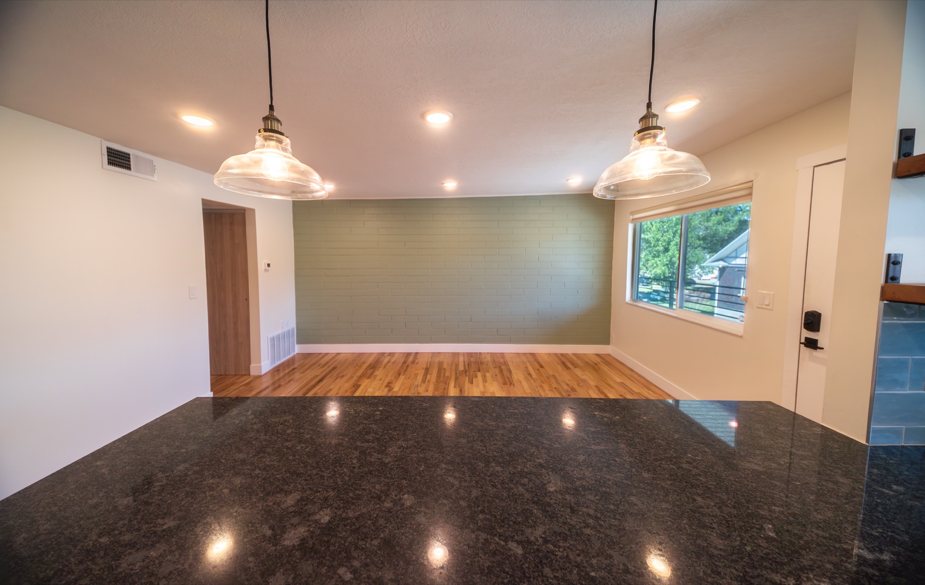 Open dining and living area with pendant lighting and hardwood floors