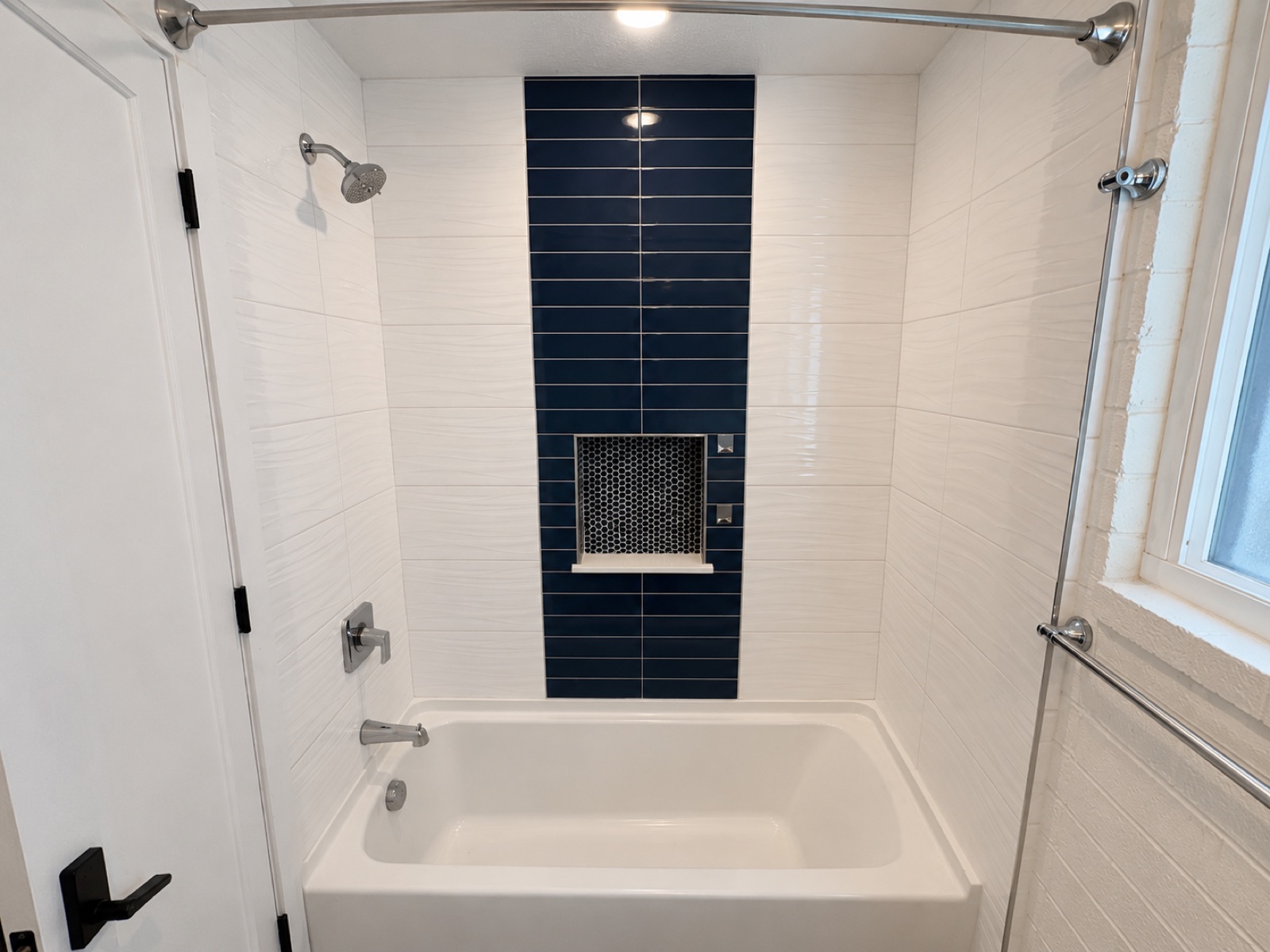 Renovated bathroom with tub, shower, and navy accent tile